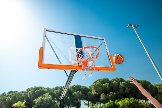 Sportif masculin jouant au basket-ball en lançant la balle au terrain de jeu