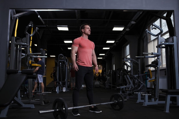 Sportif musclé fort regardant concentré debout devant une barre lourde