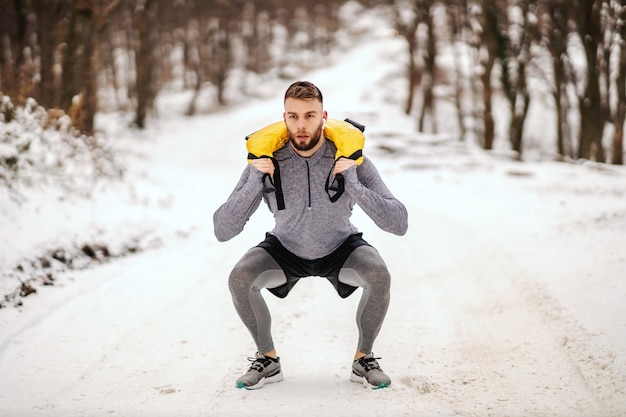 Photo sportif soulever des poids dans la nature par temps neigeux dans la nature.