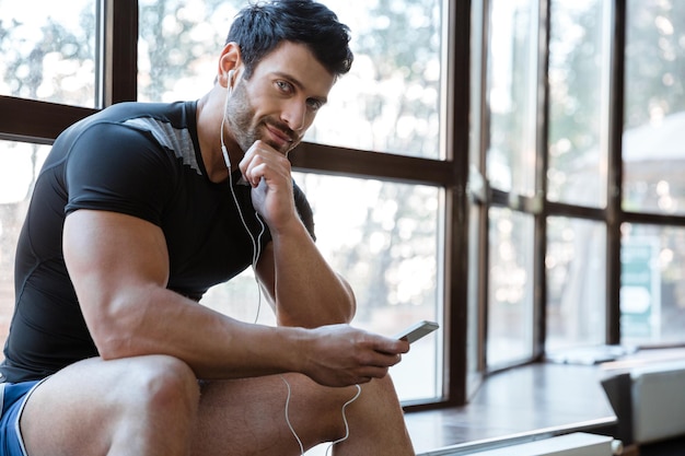 Sportif souriant portant un t-shirt noir écoutant de la musique