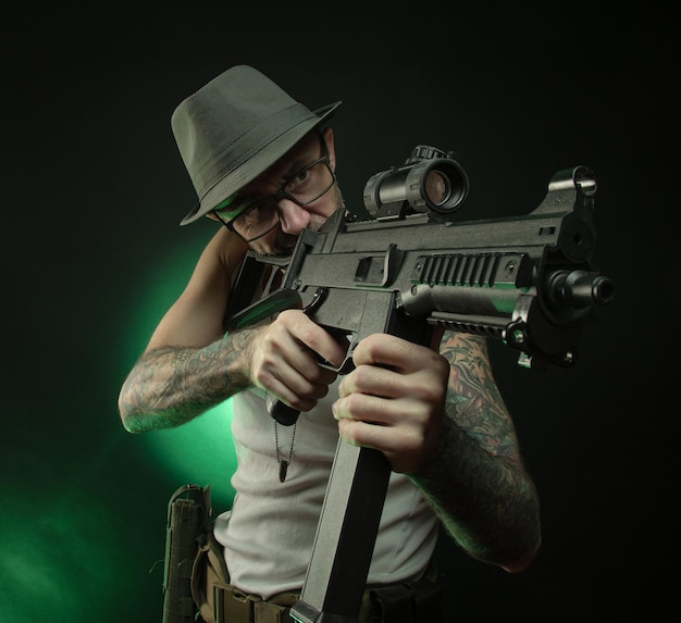 Le sportif avec un tatouage pose avec un fusil automatique