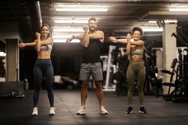 Des sportifs debout dans une salle de sport et tendant les bras