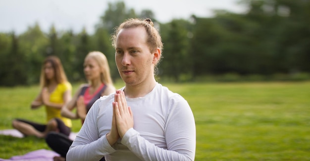 Les sportifs de yoga dans le parc - effectuent des exercices à l'extérieur en plein air le matin, prise de vue au téléobjectif