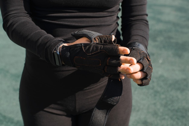 sportive dans un ensemble de sport noir enlevant ses gants noirs en gros plan