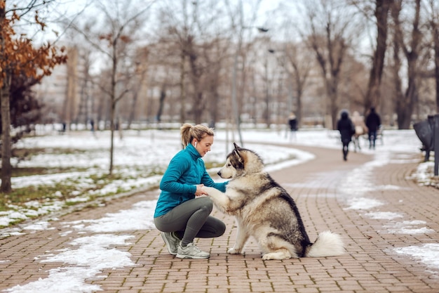 Sportive dans une promenade avec son chien dans un parc par temps froid. Neige, jour de neige, temps froid, animaux domestiques