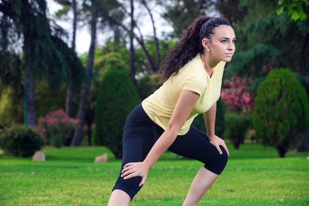 Sportive, étirement des jambes dans le parc d'été