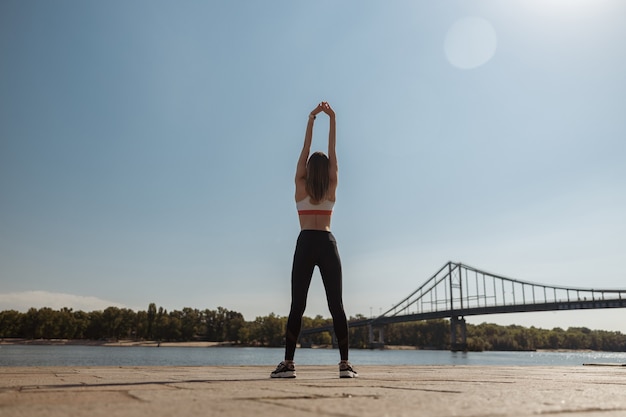 La sportive fait de l'exercice sportif sur le remblai de la ville moderne par beau temps