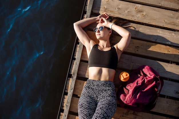 La sportive fatiguée est allongée sur la vue de dessus de la jetée en bois