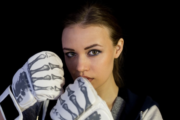 Sportive fille en gants de boxe sur fond noir.