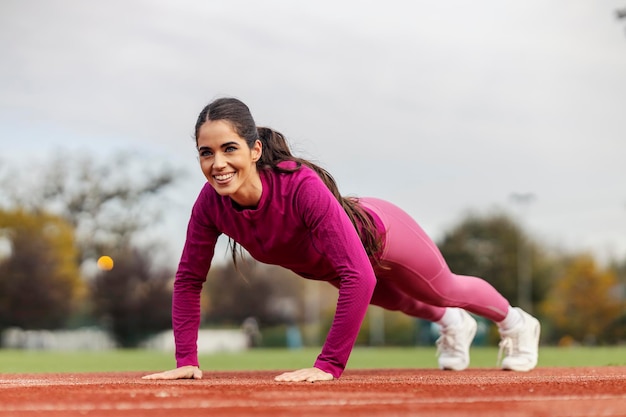 Une sportive en forme fait des pompes au stade.