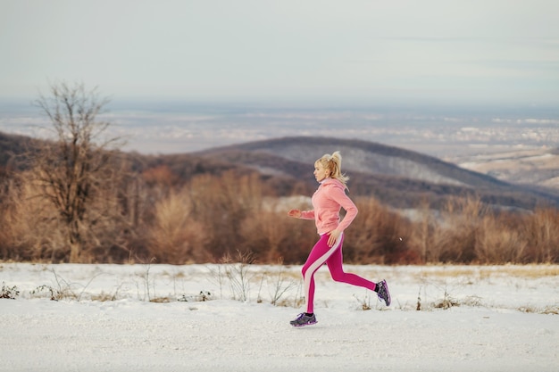 Sportive en forme de jogging dans la nature au jour d'hiver enneigé. Habitudes saines, fitness hivernal, exercices cardio