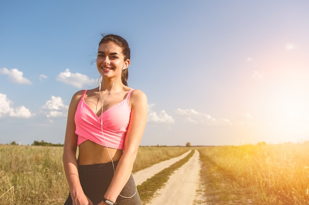 La sportive heureuse se tient sur le terrain sur le fond ensoleillé