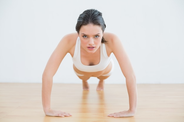 Sportive jeune femme faisant des push ups dans un studio de fitness