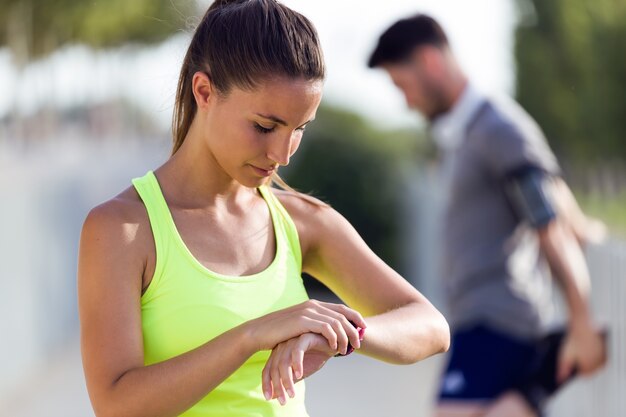 Sportive jeune femme à la recherche de son smartwatch dans la rue.