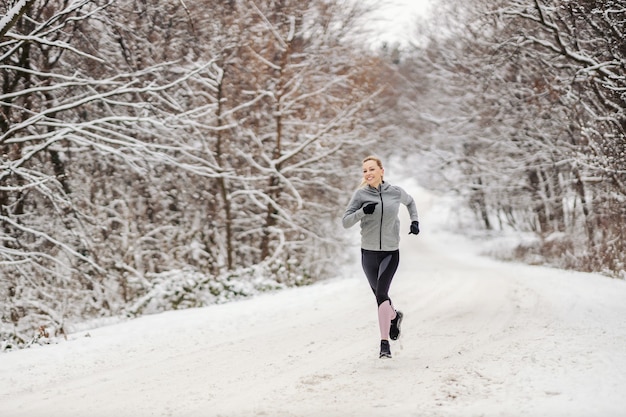 Sportive jogging dans la nature sur un chemin enneigé en hiver. Fitness d'hiver, fitness en plein air, exercices cardio