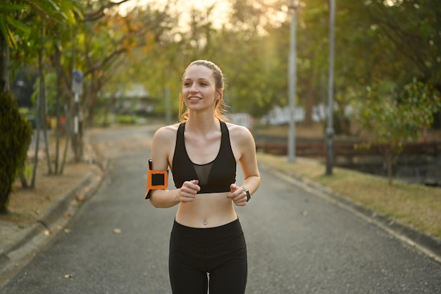 Sportive motivée courant dans le parc lors d'une belle journée d'été Entraînement physique et concept de mode de vie sain