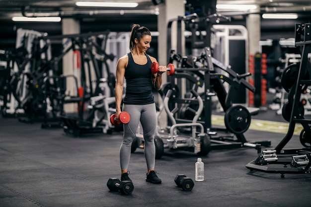 Une sportive musclée en bonne santé fléchit les muscles et fait des exercices pour les biceps avec des haltères