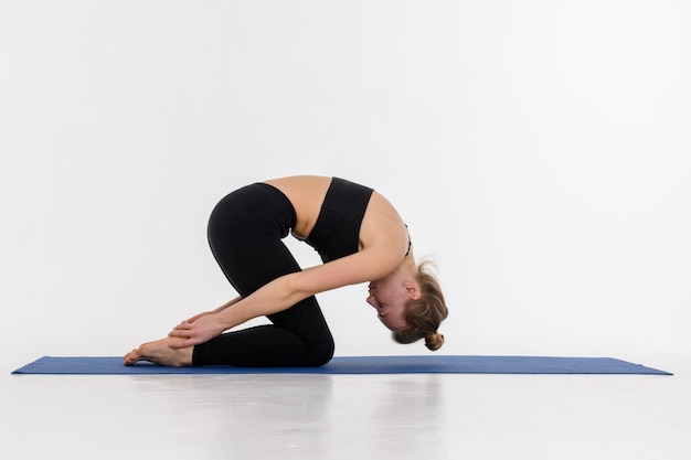 Sportive séduisante jeune femme faisant la pratique du yoga sur fond blanc.