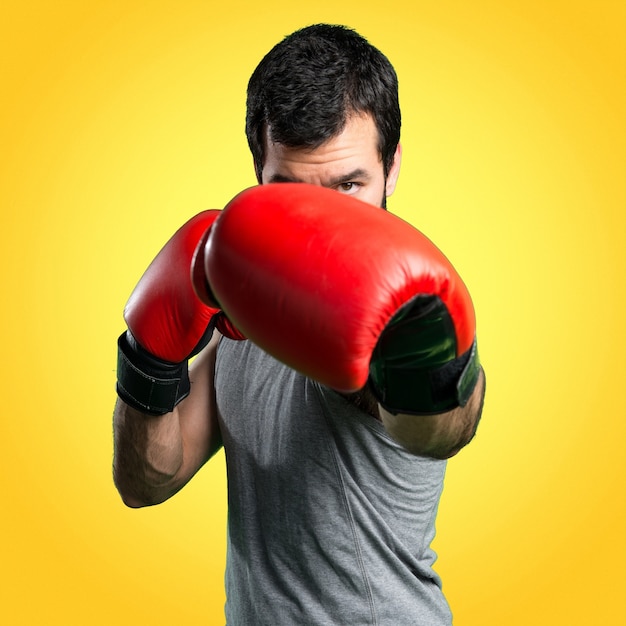 Sportman avec des gants de boxe sur fond coloré