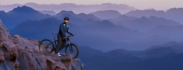 Sports brutal barbu sur un vélo de montagne moderne. Belle vue depuis la montagne.