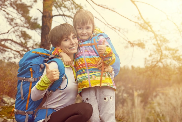 Sports famille mère et enfant avec des sacs à dos pouce vers le haut