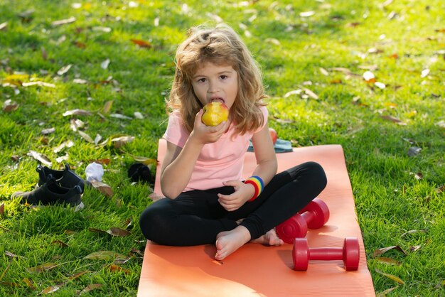 Sports sains manger pour enfant Kid garçon après le sport assis sur un tapis de sport boire de l'eau et manger