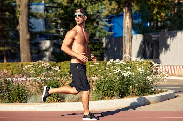 Sports urbains Homme sportif jogging torse nu pour le fitness dans le parc de la ville par une belle journée d'été