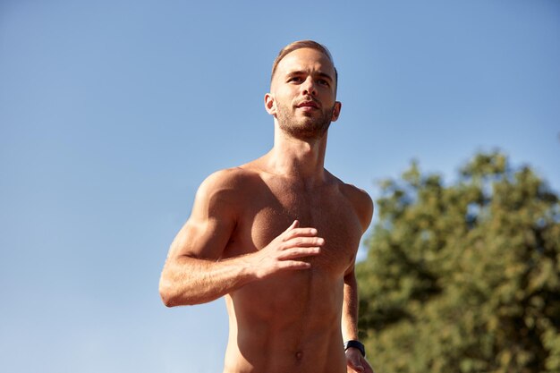 Sports urbains Homme sportif jogging torse nu pour le fitness dans le parc de la ville par une belle journée d'été