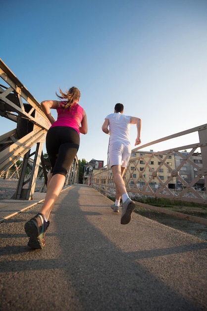 sports urbains, jeune couple en bonne santé faisant du jogging sur le pont de la ville le matin ensoleillé