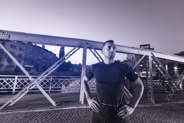 sports urbains, jeune homme en bonne santé faisant du jogging sur le pont de la ville tôt le matin dans la nuit
