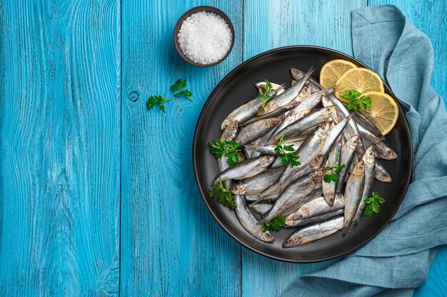 Sprat salé au citron et persil sur fond bleu