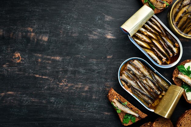 Sprats fumés dans un bocal Poisson Sur une vue de dessus de fond noir Espace de copie gratuit