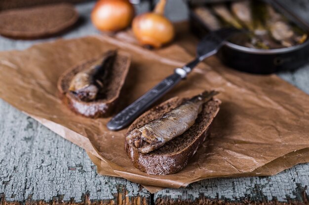 Sprats fumés avec du pain de seigle sur fond de bois