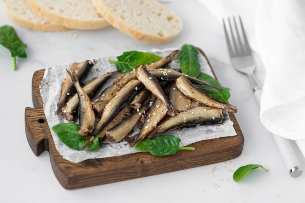 Sprats à l'huile avec des herbes sur une planche de bois