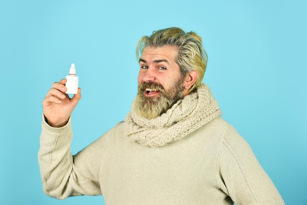 Spray nasal efficace Nez qui coule et autres symptômes du coronavirus du rhume en provenance de Chine l'homme utilise des médicaments efficaces un homme heureux tient des gouttes nasales Cela aide le concept de la grippe hipster se sent gravement malade en éternuant