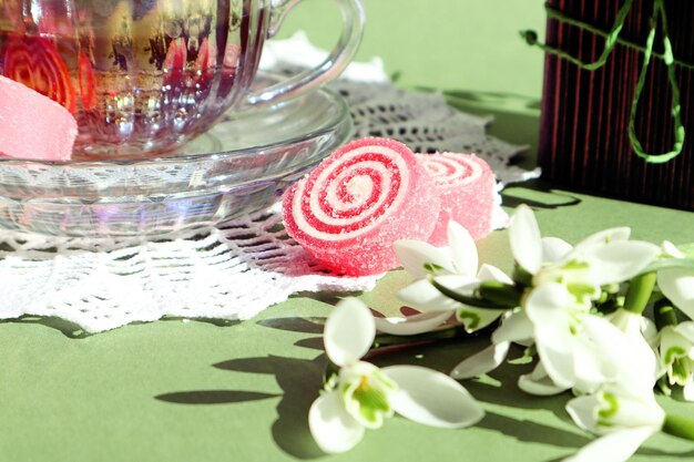 Spring tea party marmelade rose parmi les perce-neige dans le contexte d'une tasse de thé sur une serviette en dentelle blanche gros plan