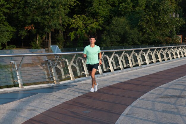 Sprinter homme athlétique en cours d'exécution dans des vêtements de sport en plein air