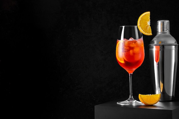 Spritz Cocktail en verre à vin avec shaker et tranche d'orange sur fond sombre