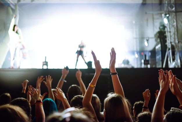 Srowd avec les mains levées au festival de musique Fans profitant d'un concert de rock avec spectacle de lumière en frappant dans les mains