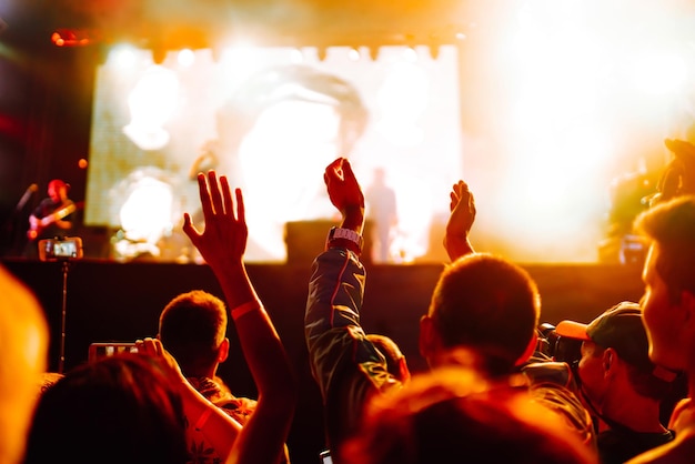 Srowd avec les mains levées au festival de musique Fans profitant d'un concert de rock avec spectacle de lumière en frappant dans les mains