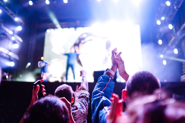 Srowd avec les mains levées au festival de musique Fans profitant d'un concert de rock avec spectacle de lumière en frappant dans les mains