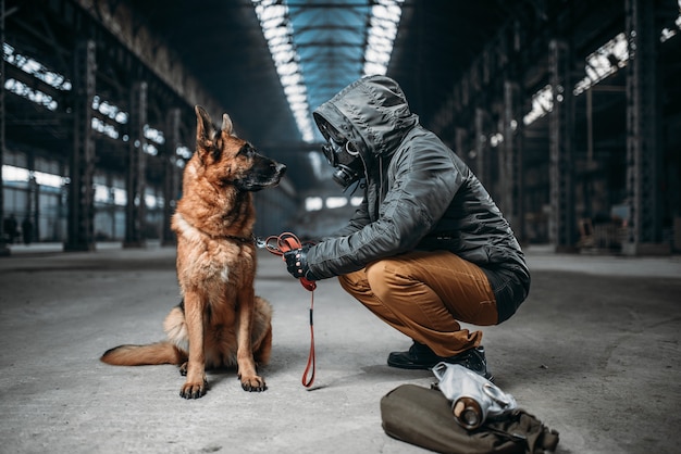 Stalker en masque à gaz et chien dans un bâtiment abandonné, survivants en zone de danger après la guerre nucléaire.
