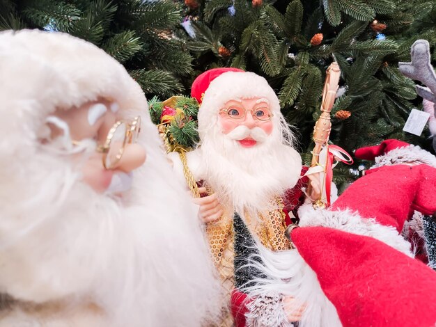 Sur le stand sous le sapin de Noël se trouvent des poupées du Père Noël dans le centre commercial.