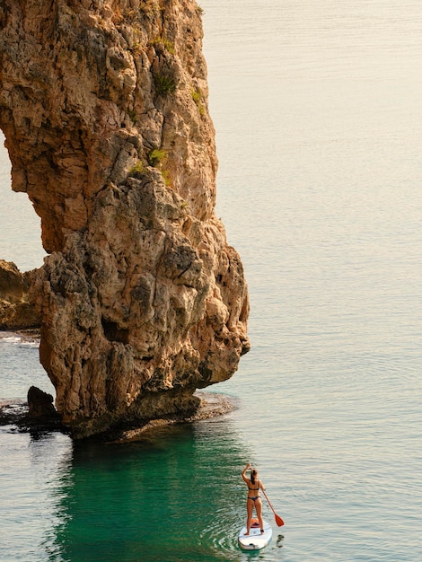 Stand up paddle jeune femme flottant sur une planche de SUP