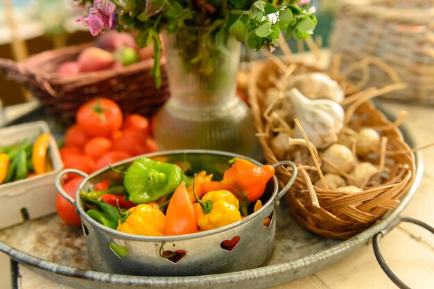 Photo un stand de vente très rustique avec des tomates, des pommes, des poivrons et des fleurs.