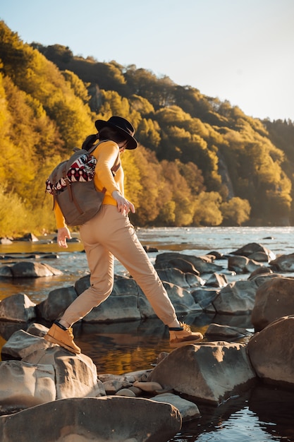 Stand de voyageur de jeune femme avec sac à dos sur fond de nature de la rivière