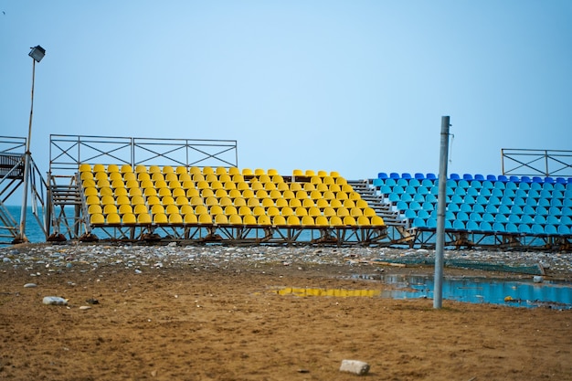 Stands déserts d'un petit terrain de sport sur la plage un jour de pluie.