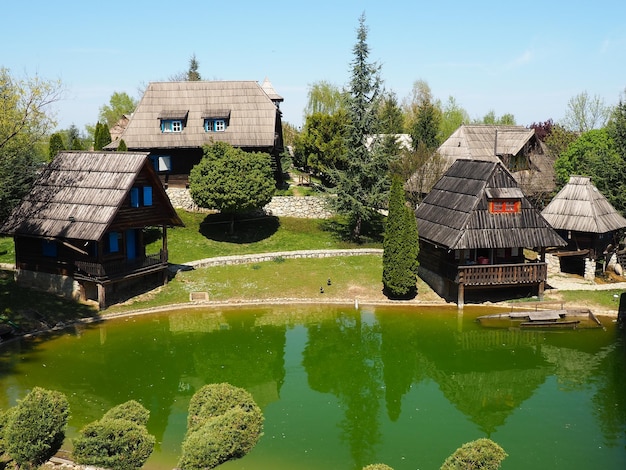 Stanisici Bijelina Bosnie-Herzégovine 25 avril 2021 Ethnovillage maisons de village traditionnelles en rondins Style bosniaque de construction dans les hautes terres Lac avec eauArchitecture en bois