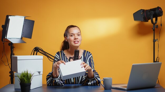 Une star des médias sociaux fait un cadeau pour les abonnés fidèles dans un studio professionnel. Vlogger expert créateur de contenu créatif enregistrant un cadeau de podcast web en ligne pour le public