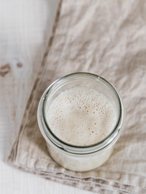 Starter de levain de blé Vue supérieure d'un récipient en verre avec un starter de levain sur un fond en bois blanc Espace de copie pour le texte ou la conception Vertical